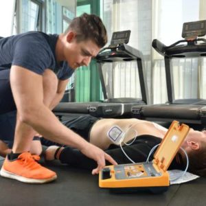 Man gebruikt AED op persoon bij loopbanden.